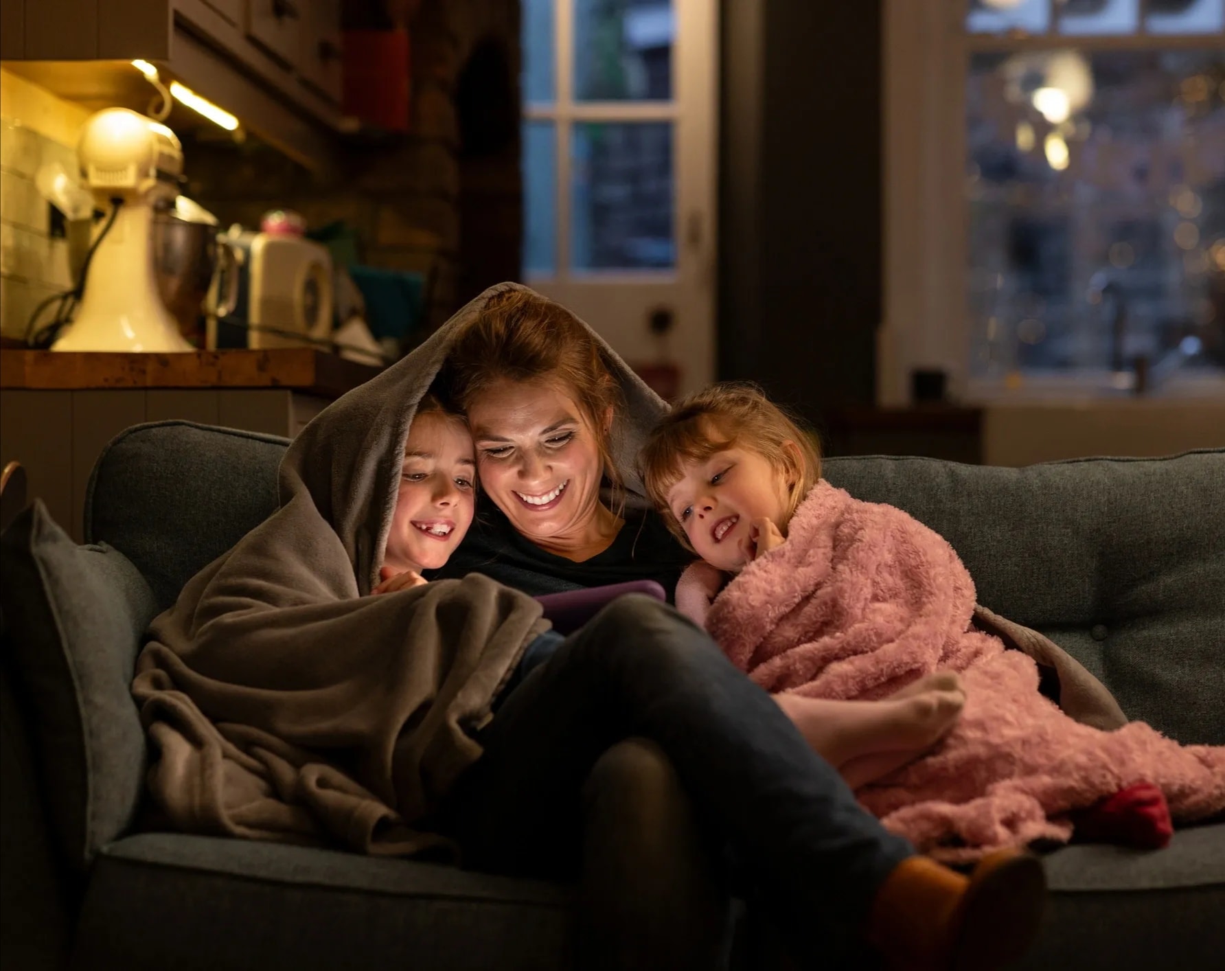 A mother and two children reading together on the couch — the kind of moment MAOZ is built for